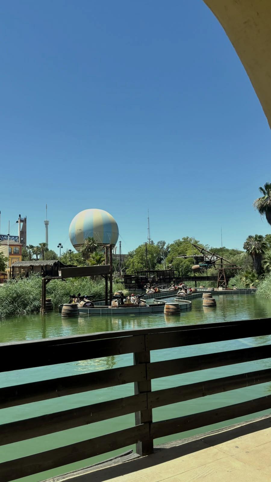 Um lago com palmeiras à volta e um balão ao fundo.